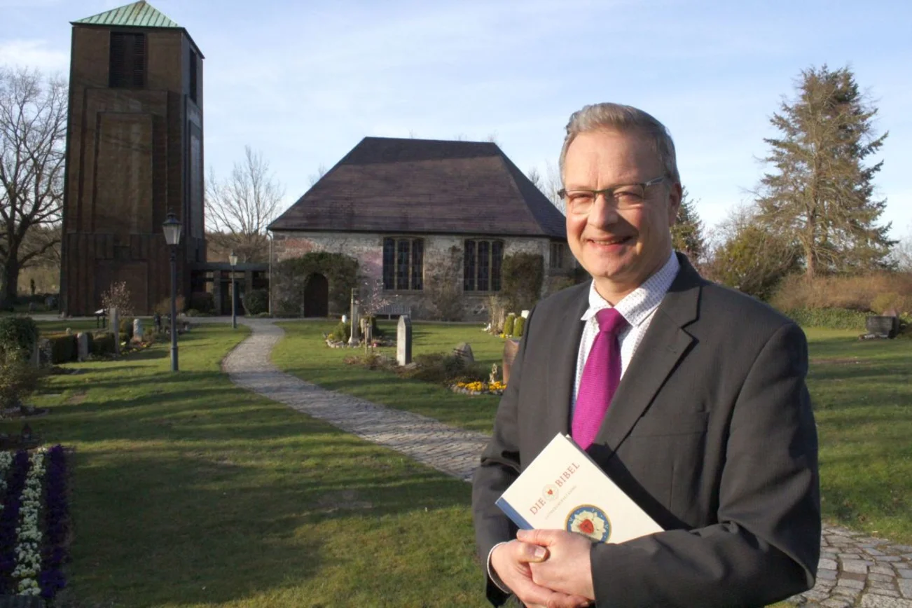 Pastor Mann vor einer Kirche.