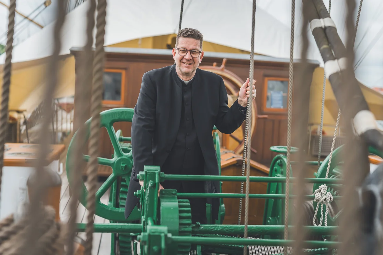 Ein Mann steht an Deck eines Segelschiffs.
