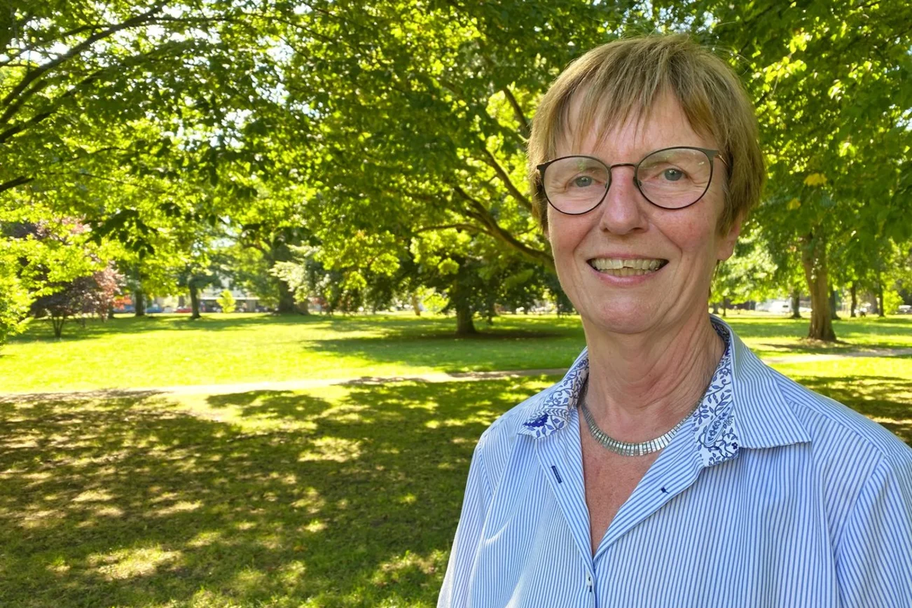 Eine Frau steht in einem sommerlich grünenden Park