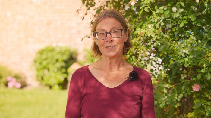 Eine Frau steht im Grünen.