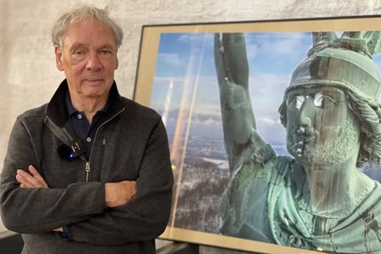 Fotograf Harald Schmitt steht vor seinem Foto des das Hermannsdenkmals bei Detmold, das gleich am Anfang der Ausstellung zu sehen ist.  - Copyright: Steffi Niemann