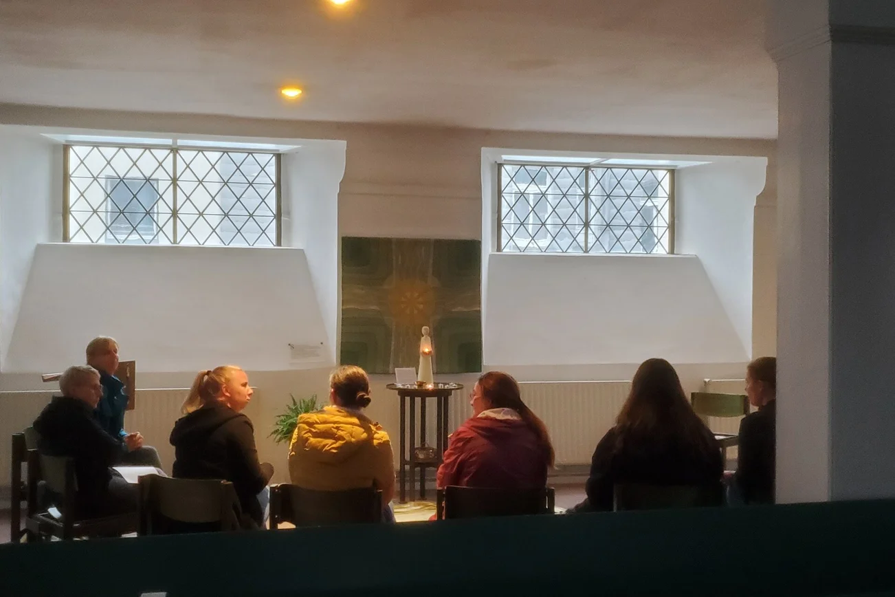 Eine Gruppe Menschen sitzt in einem Halbkreis zusammen.