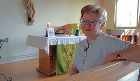 Eine Frau mit Brille und kurzen Haaren sitzt in einer kleinen Kapelle.