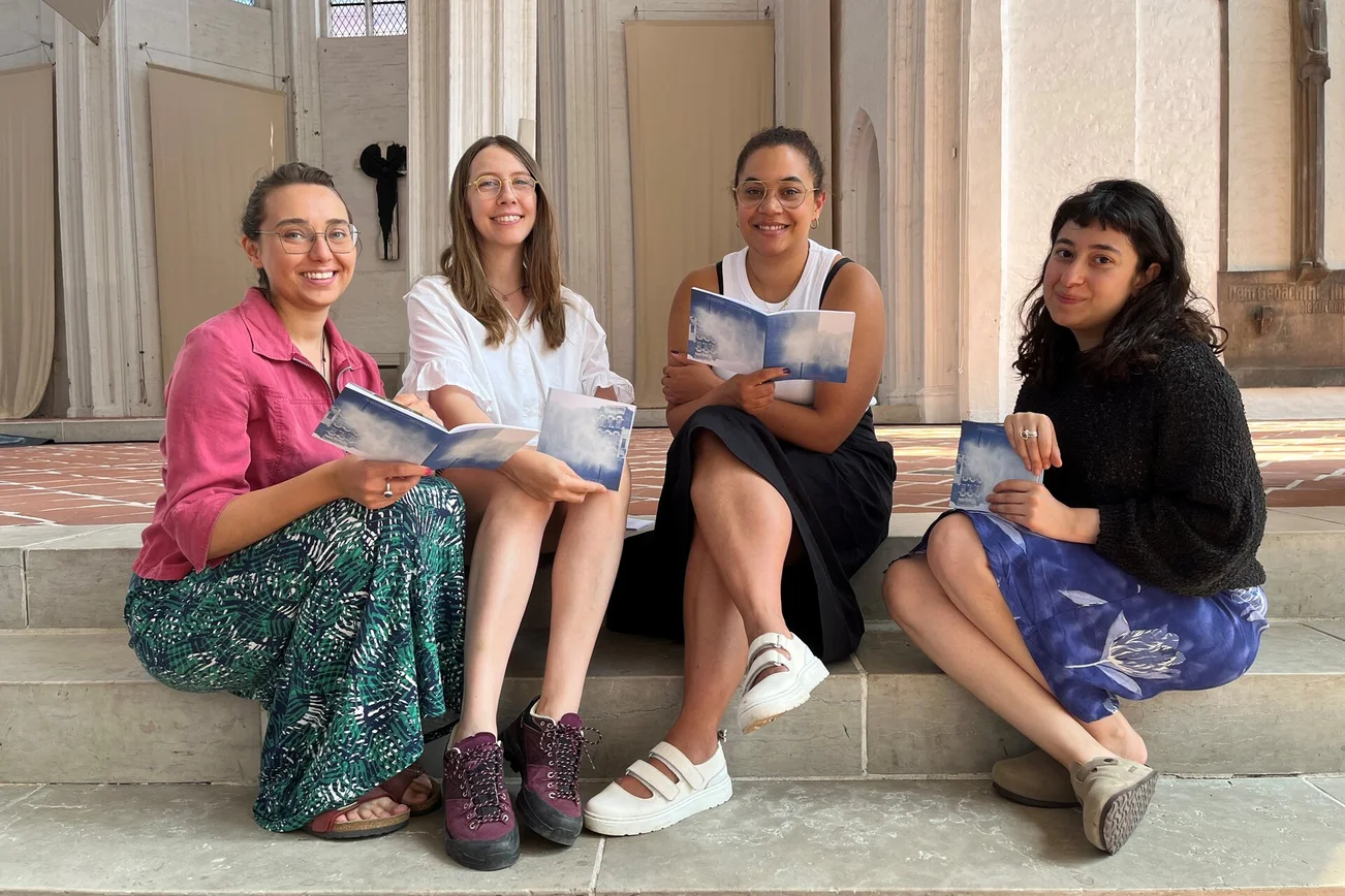 Vier frauen sitzen auf einer Treppe und lächeln in die Kamera.