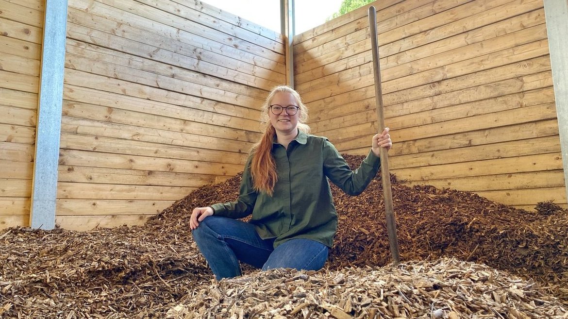 Eine Frau steht in einem mit Holzschnitzeln gefüllten Raum. 