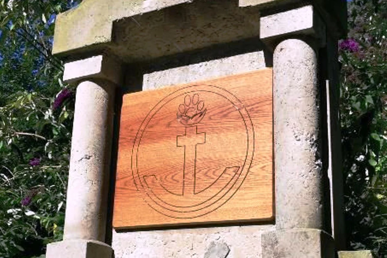 Ein Anker und eine Tierpfote sind auf einer Holztafel eingeschnitzt. 