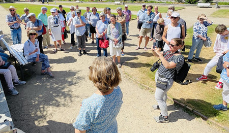 Eine Gruppe Menschen versammelt im Kreis bei Sonnenschein