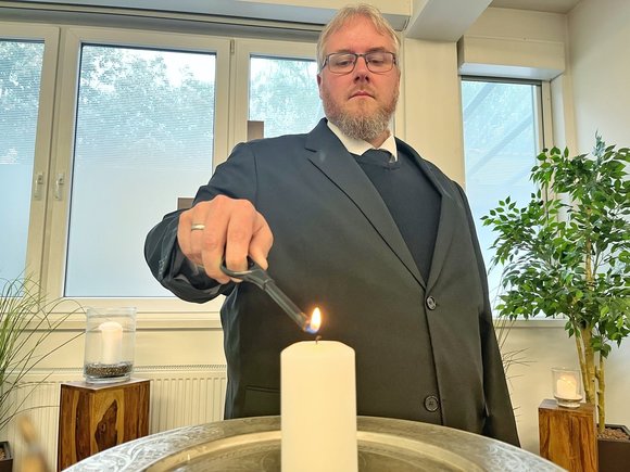 Ein Mann entzündet eine Kerze