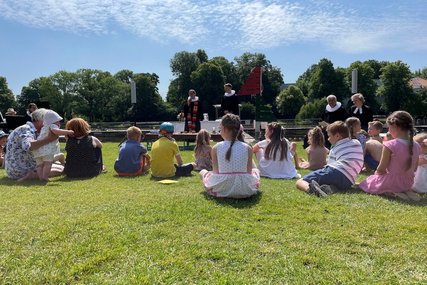 Das Tauffest 2023 im Altstadtbad Krähenteich. Vorne sind Kinder mit ihren Familien sitzend, im Hintergrund Pastorinnen und Pastoren zu sehen.  - Copyright: Mike Bergbauer