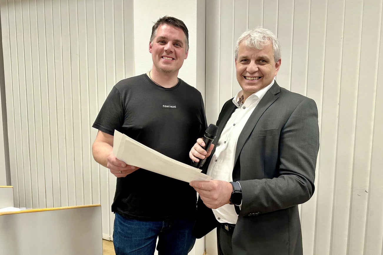 Zwei Männer stehen in einem räum und lächeln in die Kamera