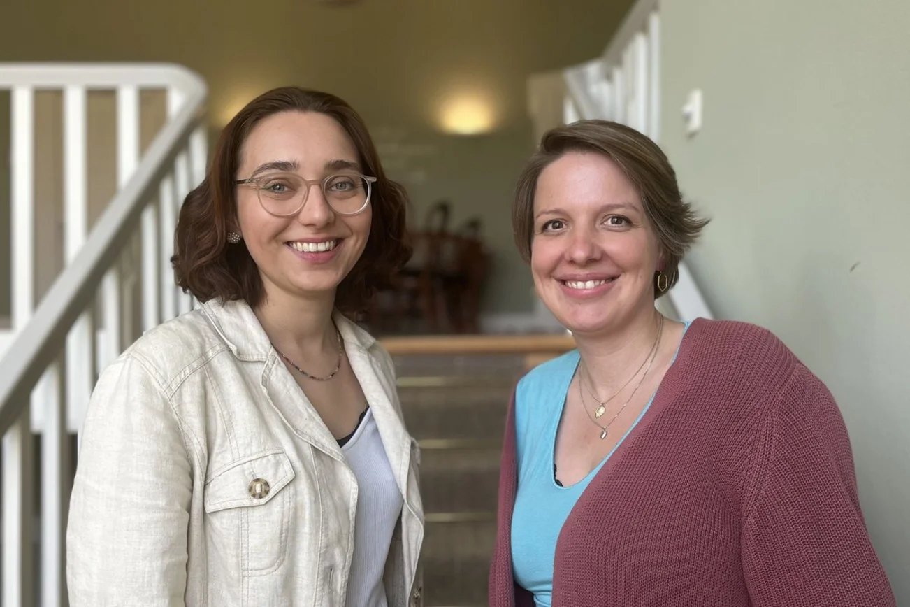 Zwei Frauen stehen auf einer Treppe und lächeln in die Kamera
