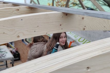 Eine junge Frau schaut zwischen den Deckenbalken eines Bauwagens hervor. - Copyright: Lisa Feil/ 'Wohlmühle'