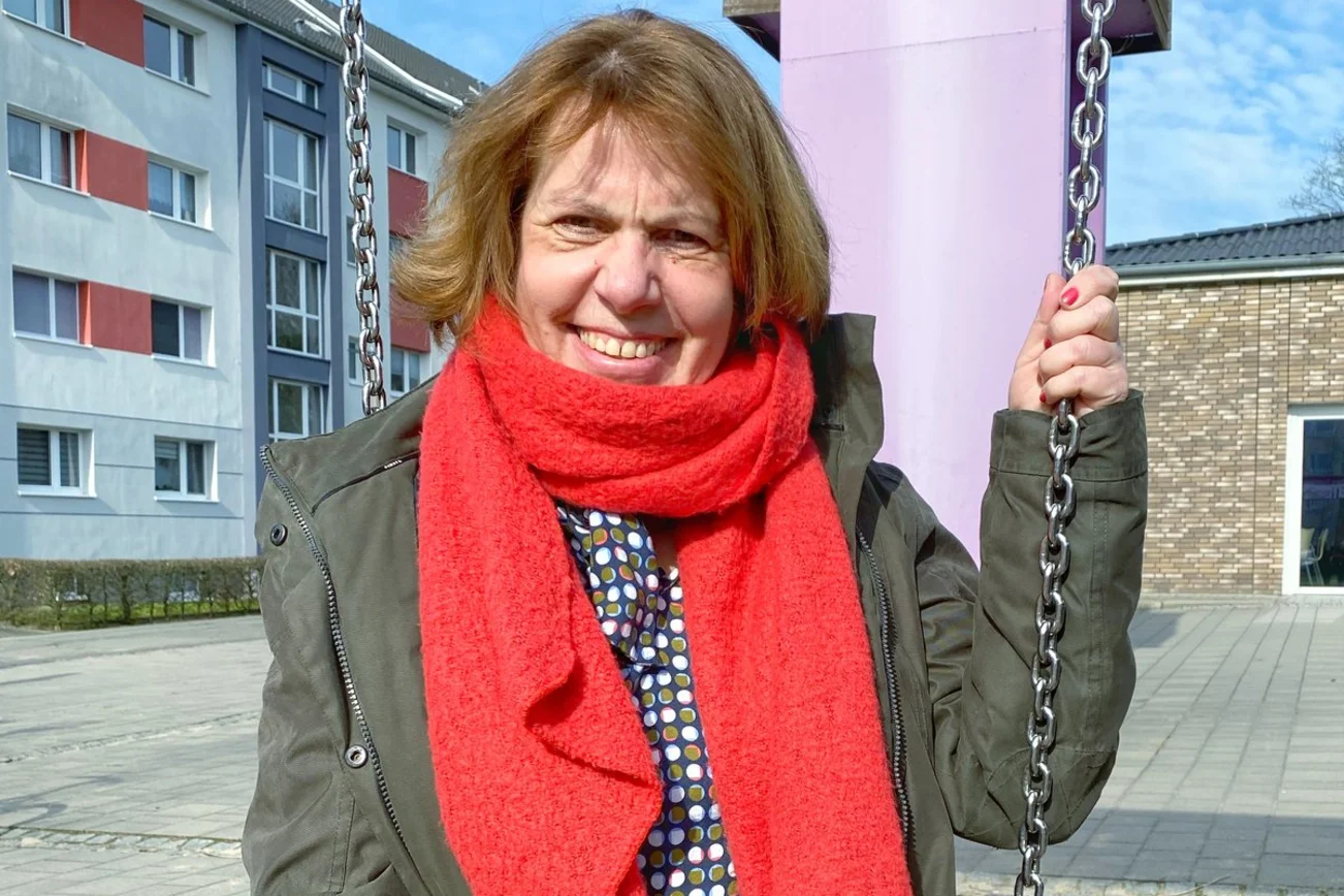 Eine Frau sitzt lächelnd auf einer Schaukel.