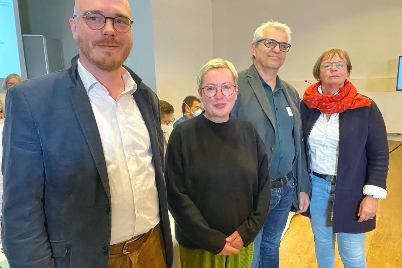 Vier Personen lächeln in die Kamera. 