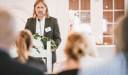 Ein Mann steht am Podium und hält eine Rede.