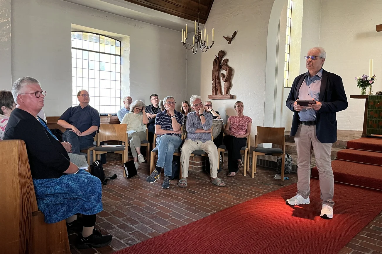 Ein Mann spricht in einer Kirche vor einer Versammlung.