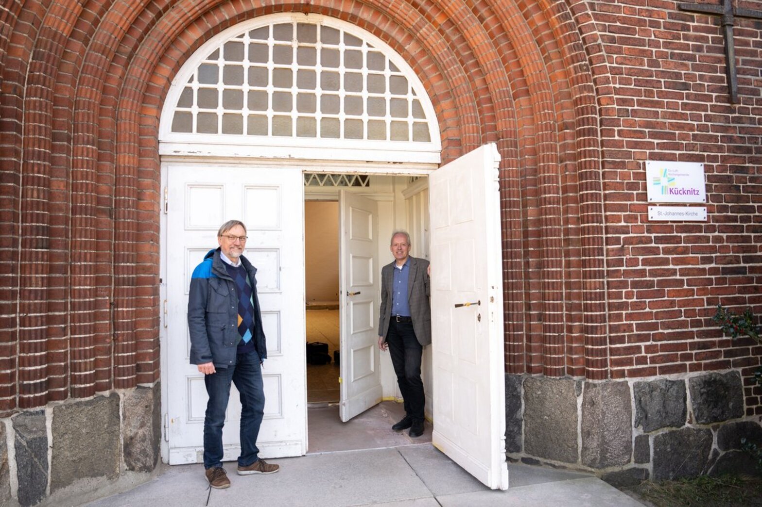 Zwei Männer stehen am Eingang einer Kirche.
