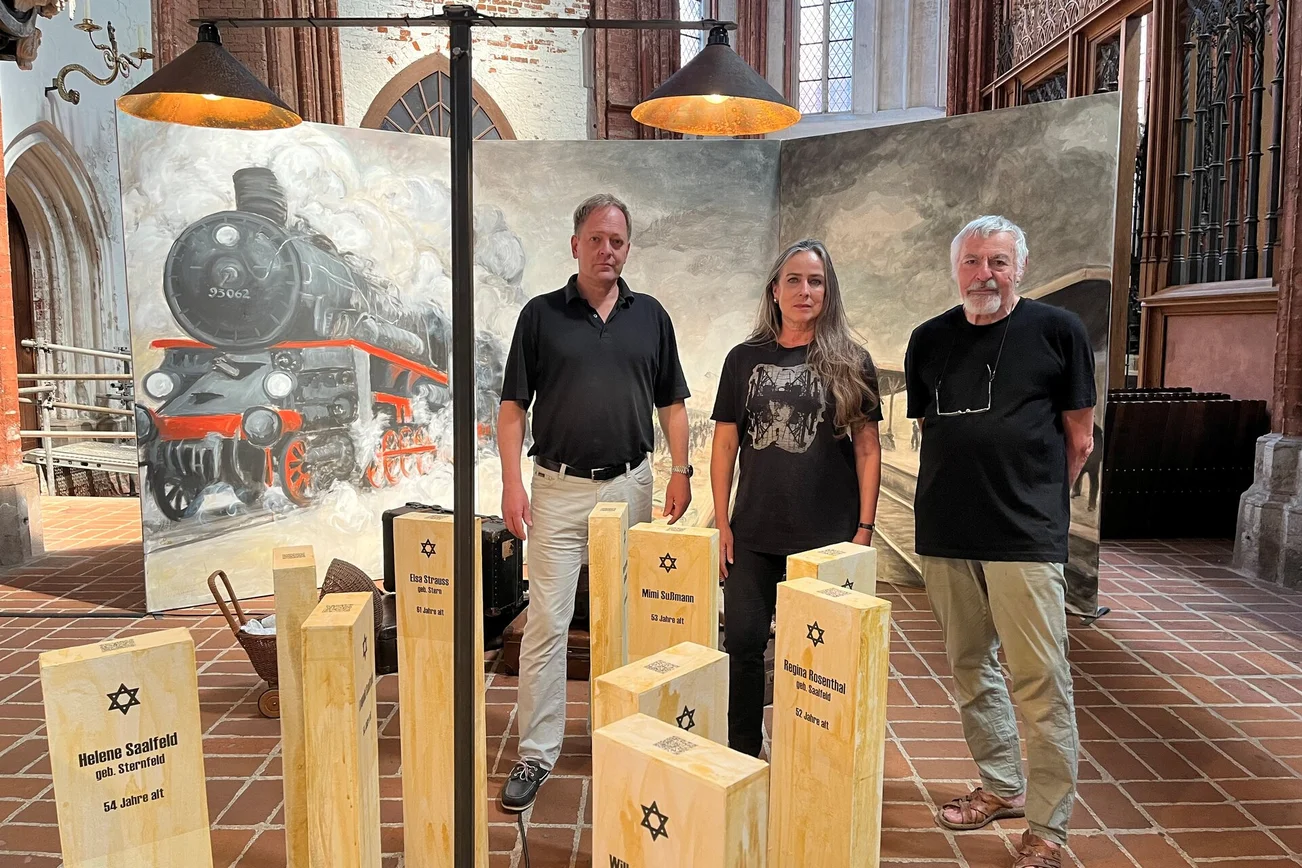 Drei Menschen stehen vor einem Gemälde und hinter einer Kunstinstallation