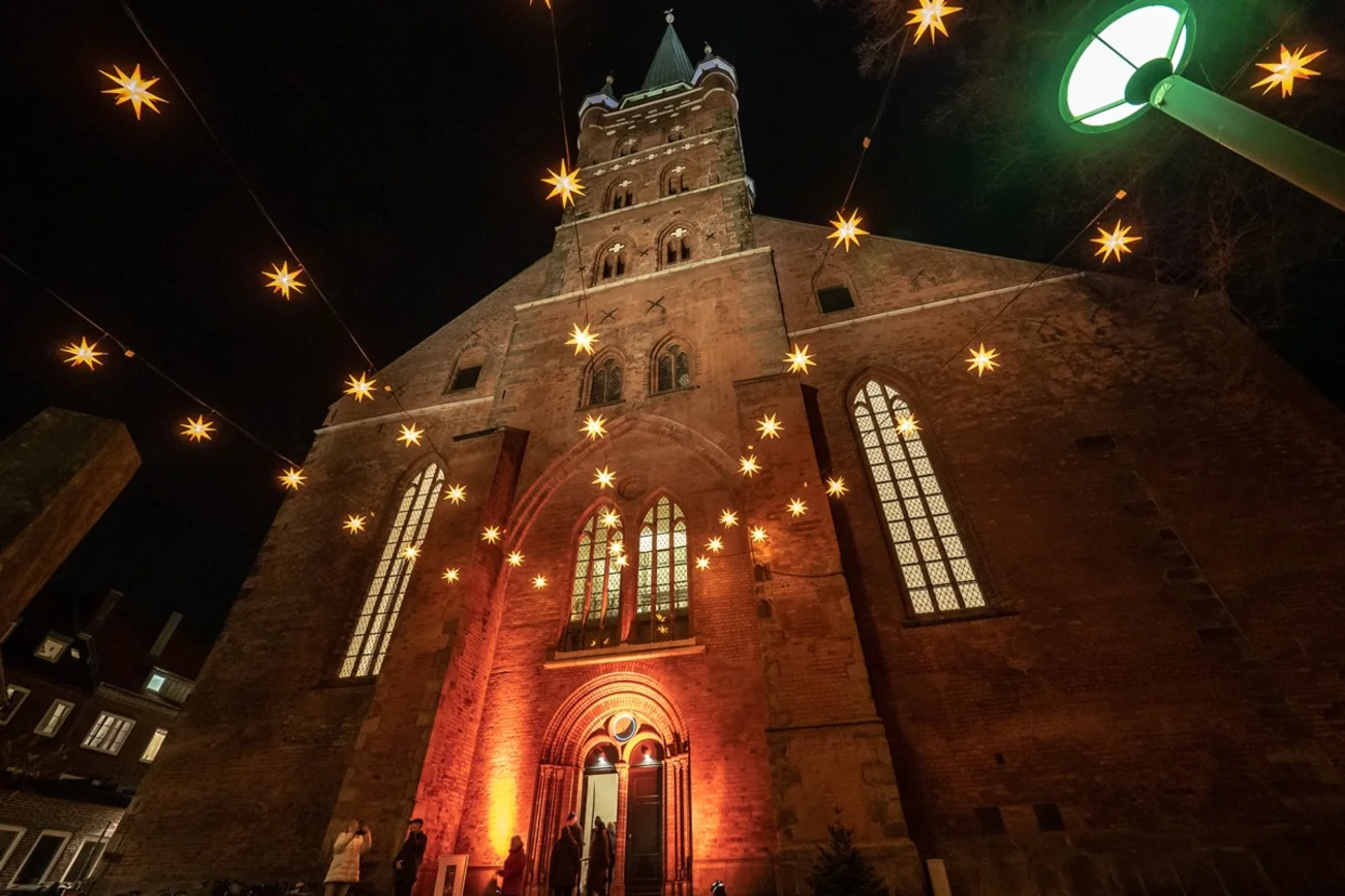 Die Petrikirche am Abend. Davor leuchtende Herrnhuter Sterne.