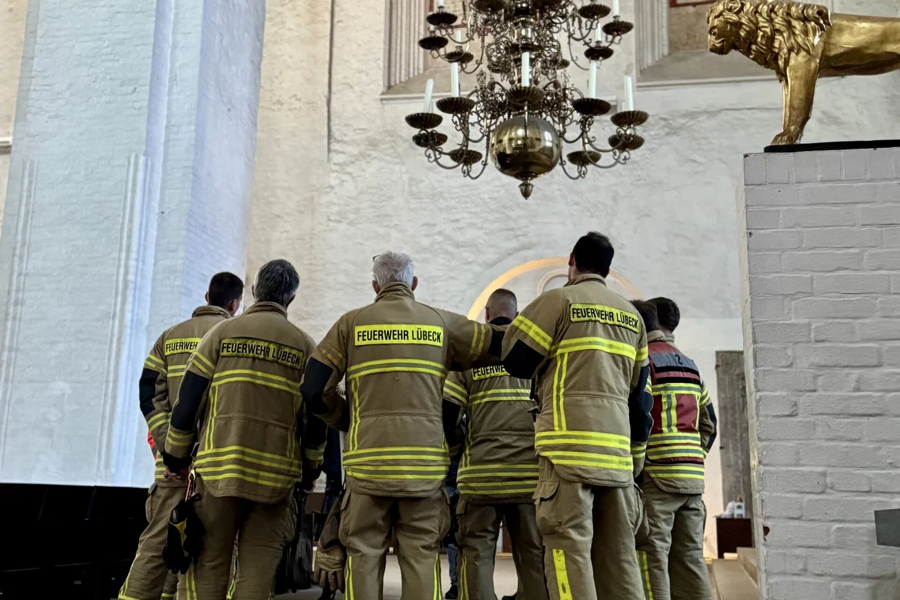 Feuerwehr Leute stehen unter einem alten Leuchter in einer Kirche.