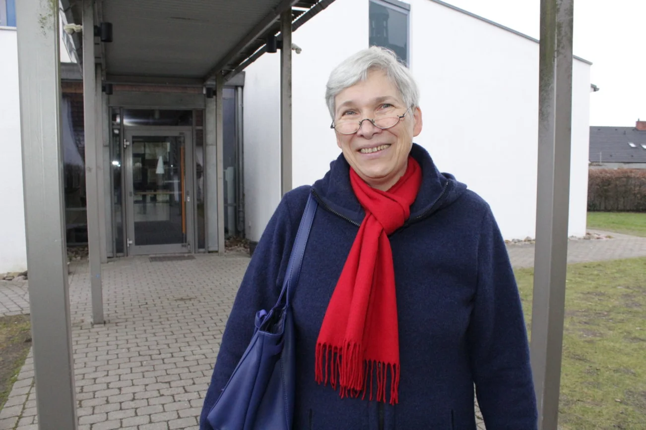 Eine Frau steht vor einem Gebäude. 