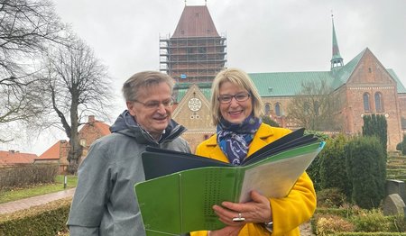 Zwei Personen stehen mit einer Planungsmappe vor dem Ratzeburger Dom.