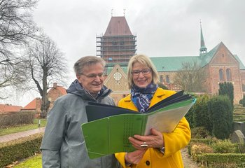 Zwei Personen stehen mit einer Planungsmappe vor dem Ratzeburger Dom. - Copyright: Bastian Modrow