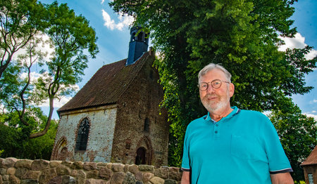 Ein Mann steht vor einer Kapelle