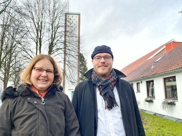 Zwei Personen vor einer Kirche im Winter.