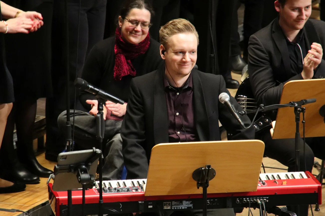 Ein Musiker sitzt an einem Keyboard und lächelt.