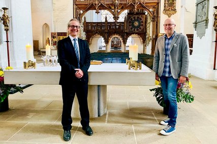 Die beiden Küster stehen im Dom am Altar und lächeln in die Kamera. - Copyright: Steffi Niemann