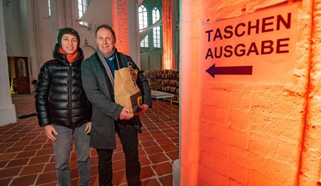 Zwei Personen stehen in St. Petri und lächeln in die Kamera. 