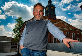 Ein mann steht vor einer Kirche und lächelt in die Kamera.  - Copyright: Bastian Modrow