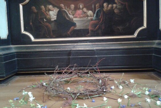 Dornenkranz mit Blüten auf dem Altar vor einem Bild vom Abendmahl - Copyright: Ev.-Luth. Kirchengemeinde Krummesse