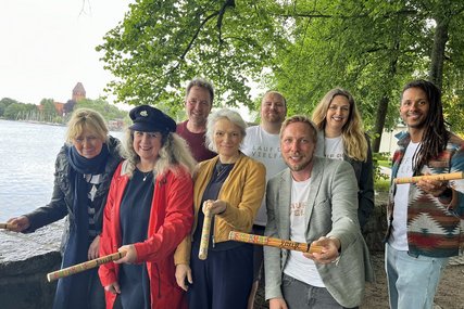 Mehrere Menschen stehen an einem See und halten Staffelstäbe in den Händen. - Copyright: Annkathrin Bornholdt