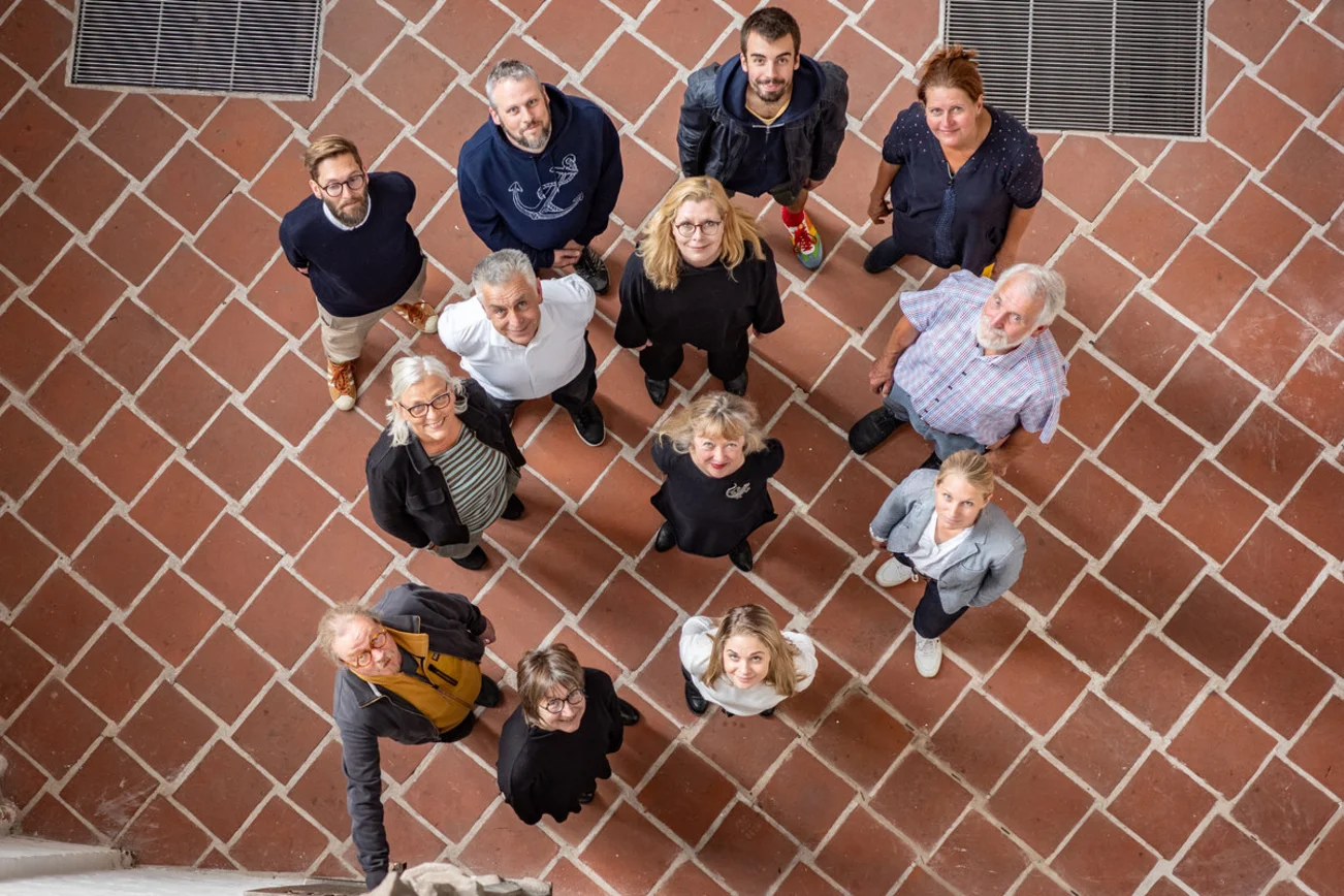 Menschen stehen in einem Raum und blicken nach oben. 