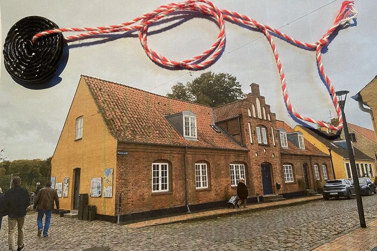 Eine Lakritzschnecke an einer Kordel liegt auf dem Foto eines Hauses. 