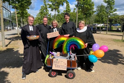 Fünf Menschen in Talar hinter einem gefüllten Bollerwagen. - Copyright: Katharina Micheel