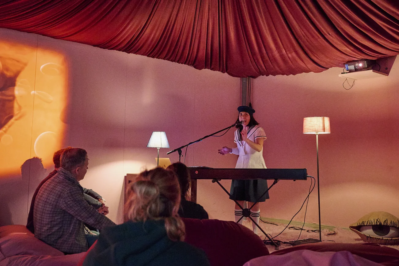 Eine Frau im Matrosen-Kleid steht in einem schummrig beleuchteten Raum an einem Keyboard.