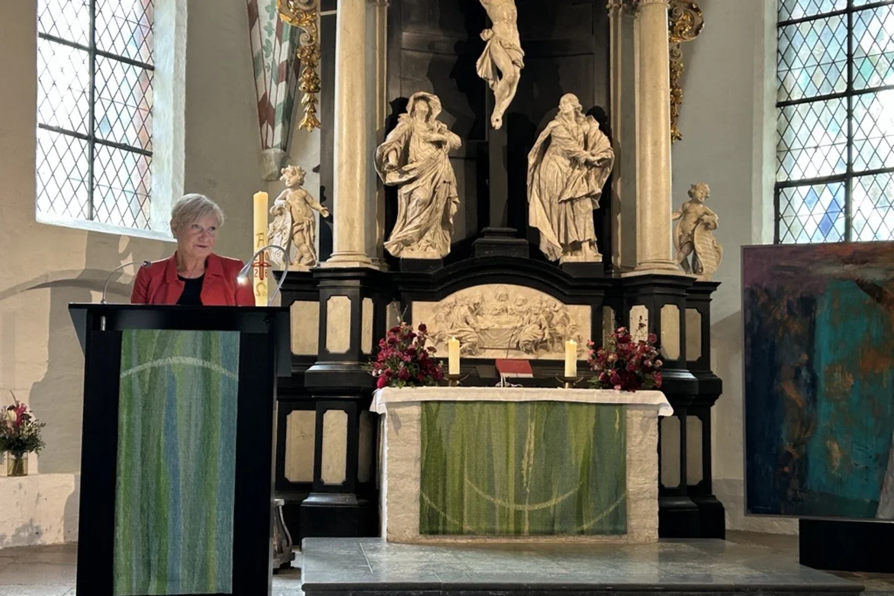 Eine Frau steht an einem Pult in einer Kirche.