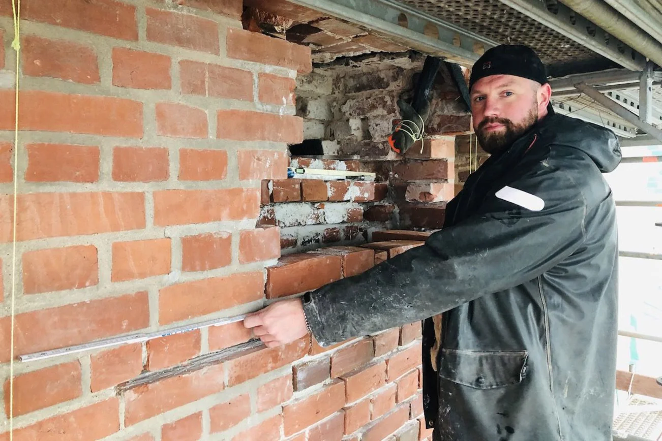 Kirchenbauhütten-Leiter Marco Quandt erklärt die Maurerarbeiten anhand des Loches, das bis zur historischen Mauer aufgestemmt wurde. 