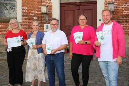Fünf Personen stehen nebeneinander und halten Flyer und gucken zum Betrachter. - Copyright: Thomas Biller