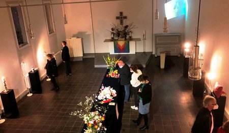 Ein Kirchraum von der Empore mit Blick auf den Altar fotografiert. Menschen schauen sich die Ausstellungsstücke an.
