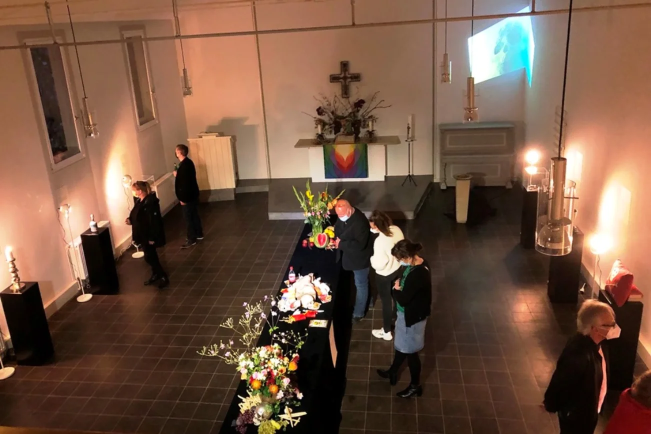 Ein Kirchraum von der Empore mit Blick auf den Altar fotografiert. Menschen schauen sich die Ausstellungsstücke an.