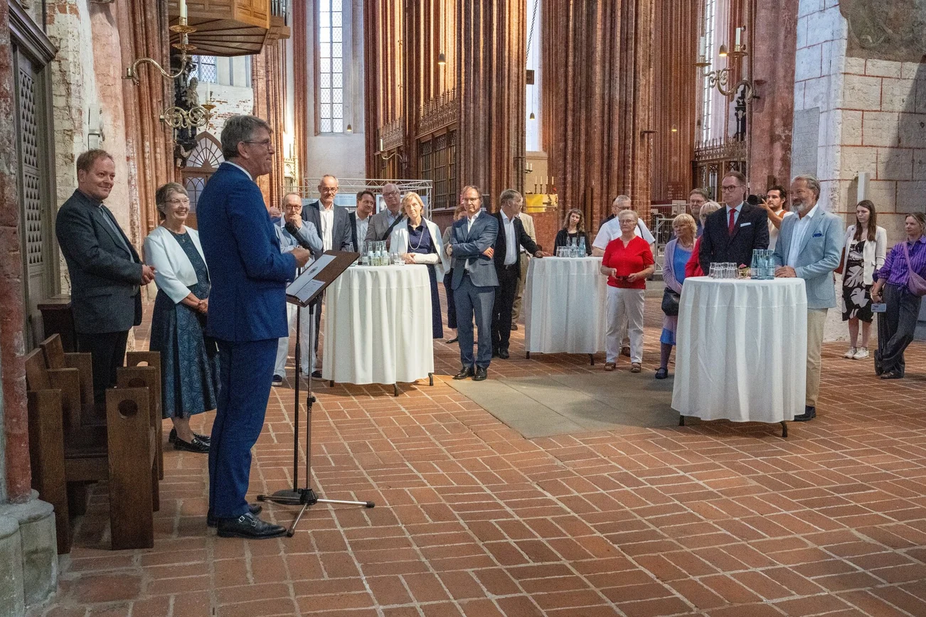 Menschen stehen in einer Kirche an Stehstischen