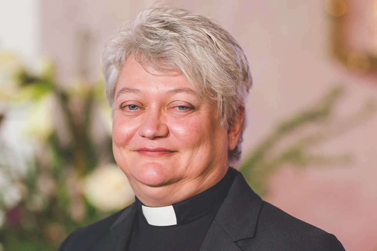 Eine Pastorin schaut lächelnd in die Kamera.
