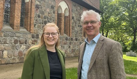 Eine Frau und ein Mann stehen vor einer Kirche-