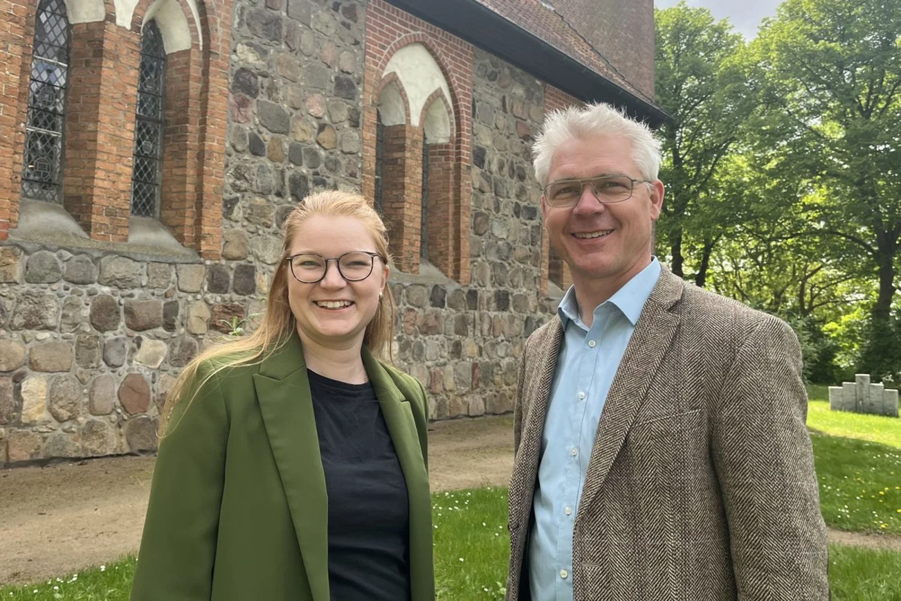 Eine Frau und ein Mann stehen vor einer Kirche-