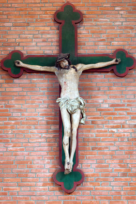 mittelalterlicher gestorbener Christus am neuen Kreuz vor Ziegelsteinwand