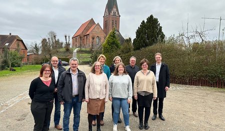 Mehrere Personen im Vordergrund, im Hintergrund Kirche